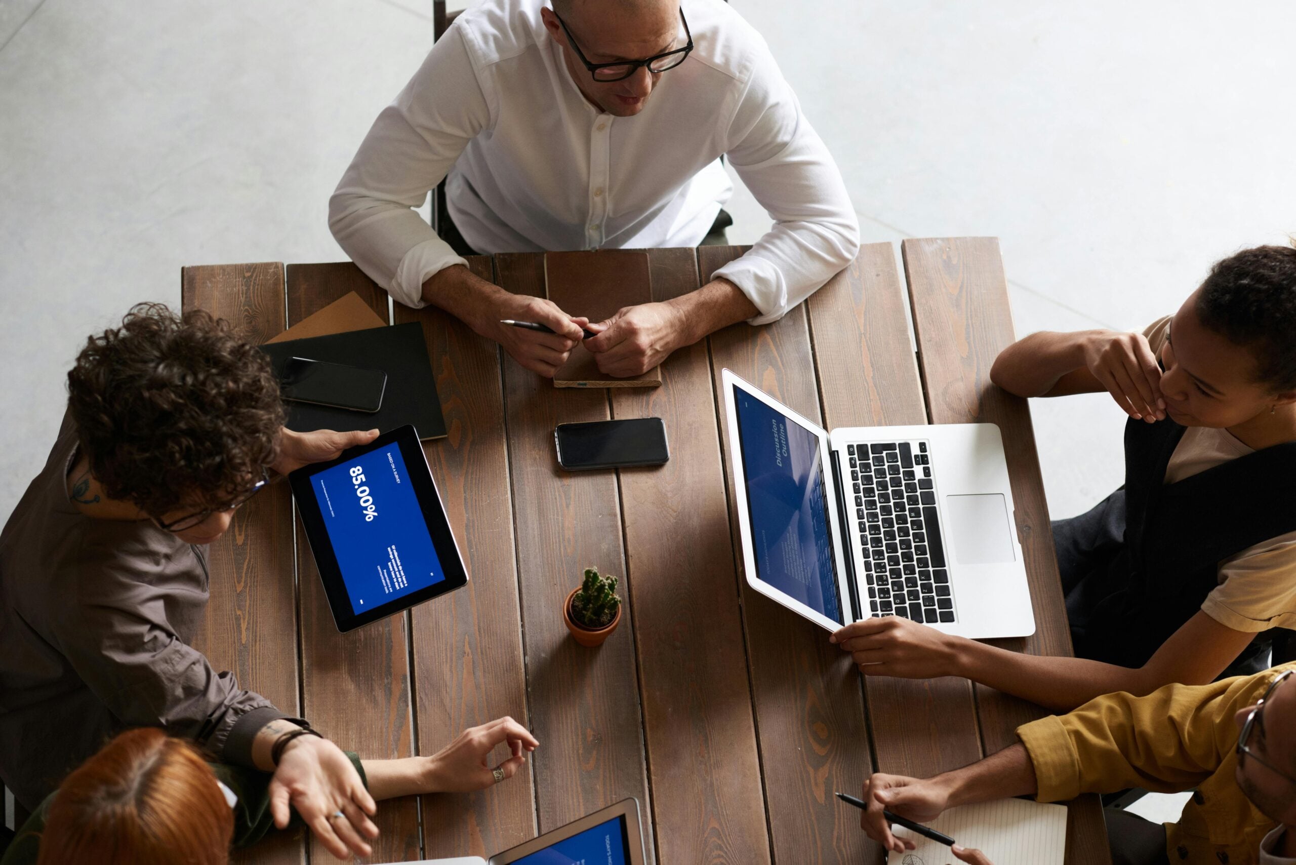 Colleagues negotiating around a table with laptops, representing deal structuring and negotiation in regulated sectors